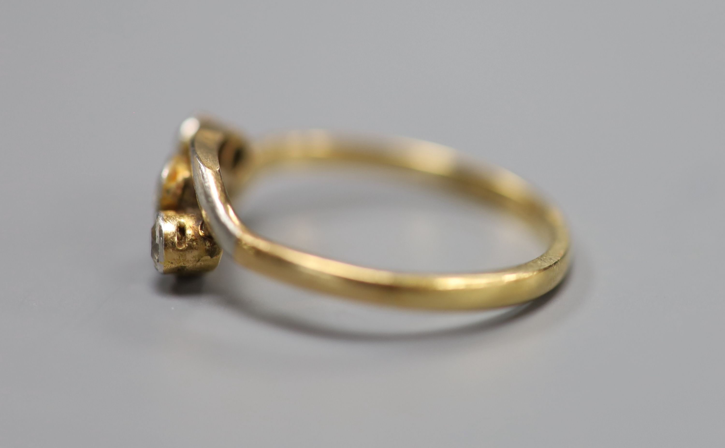 An 18ct and three stone diamond set crossover ring, size Q, gross 2.4 grams.